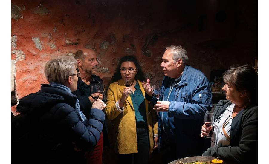 Cinq personnes, en cercle, sont en train de discuter autour d'un verre de vin